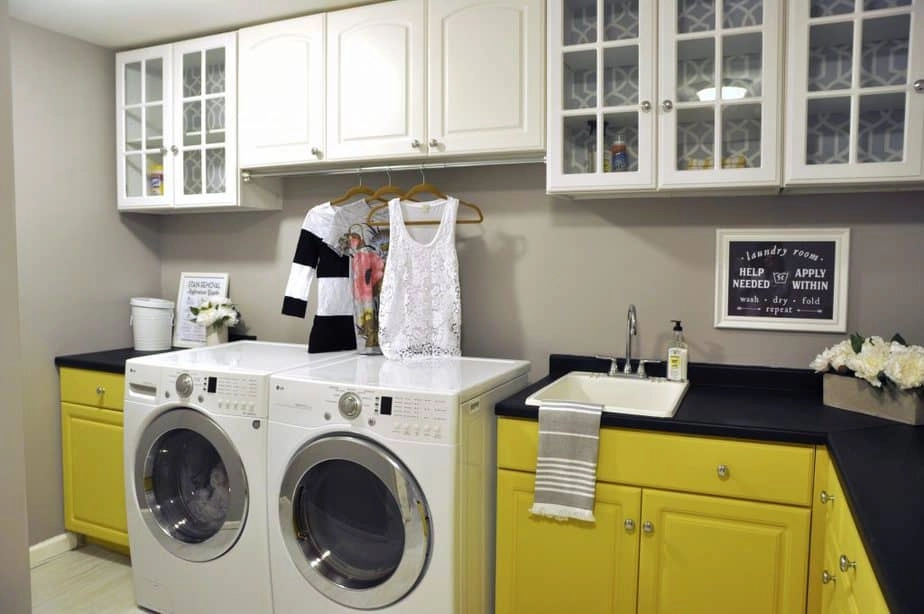 A look at our laundry room makeover with yellow painted lower cabinets, black countertops, and updated upper cabinets.