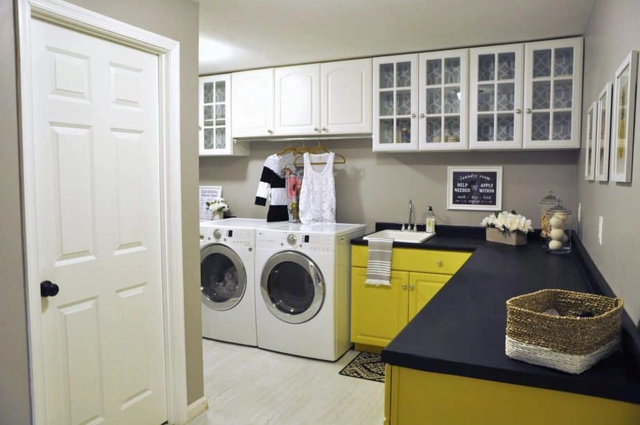 A look at our laundry room makeover with yellow painted lower cabinets and black countertops painted with chalk paint.