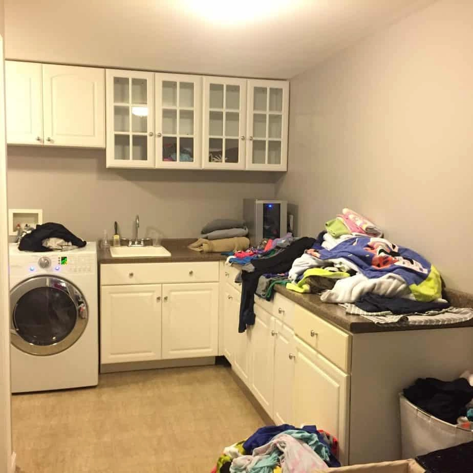 Our plain laundry room before the makeover - boring countertops cluttered with clothes.