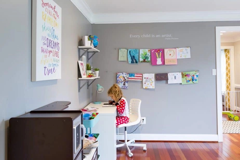 An easy way to display kids artwork at home: here's a look at one wall of our kids playroom, the artwork wall with two rows of picture wire, filled with kids art.