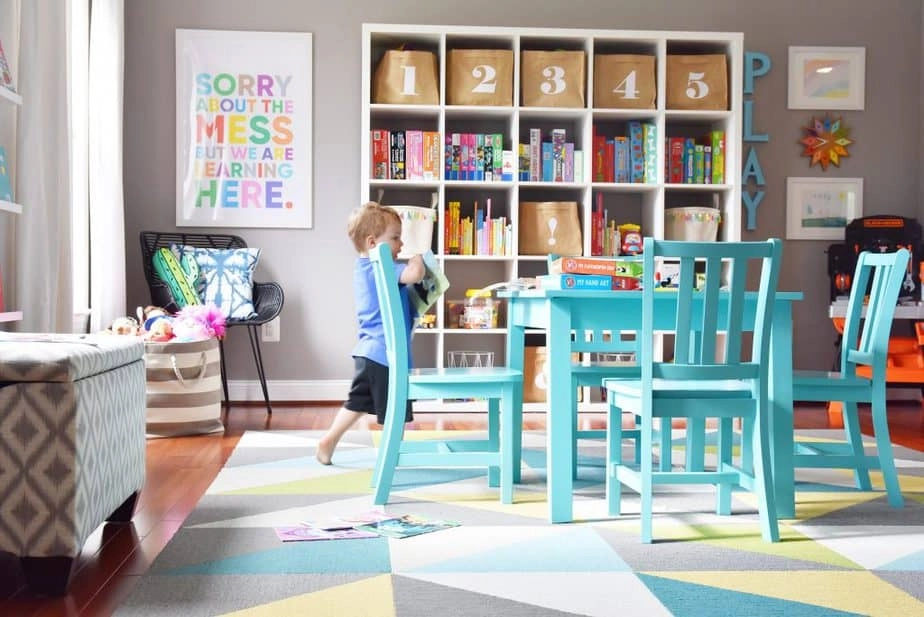 A look at our decluttered kids playroom right after cleaning and organizing, with a cubicle bookshelf for toy storage, storage bins, and a kid-sized table.