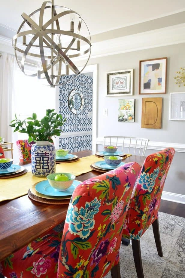 A brightly-lit dining room with IKEA Henriksdal chairs covered in bright coral floral slip covers, colorful place settings, and modern decor.