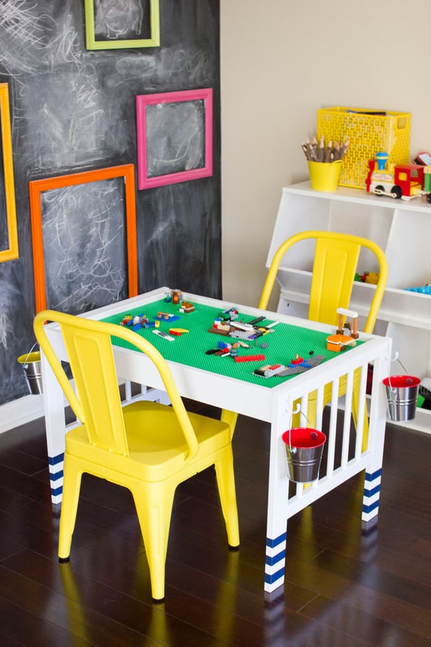In this kid-friendly IKEA hack, an IKEA changing table is transformed into a lego table for kids, painted white with a LEGO table top and yellow plastic chairs in a kids playroom.