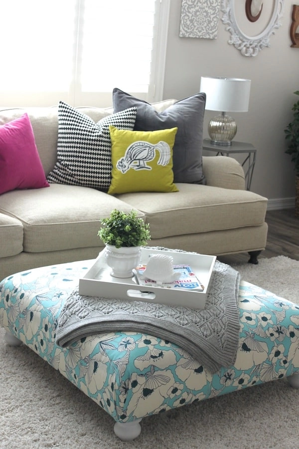 This IKEA ottoman was upgraded until a gorgeous centerpiece using blue, white, and black abstract floral fabric.