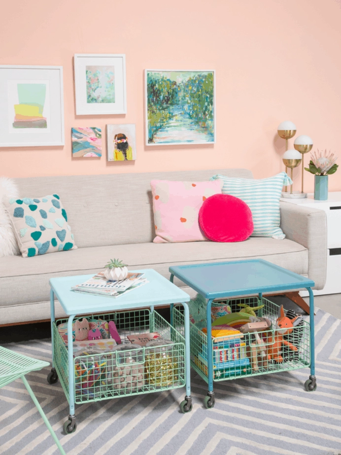 A pair of IKEA rolling storage tables are painted light blue and teal, and hold neatly organized kids toys.