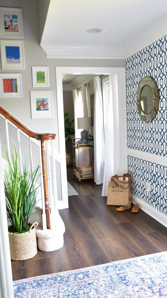 Our updated entryway makeover completed with new wallpaper, a floor plant, area rug, and a new round wall mounted mirror.