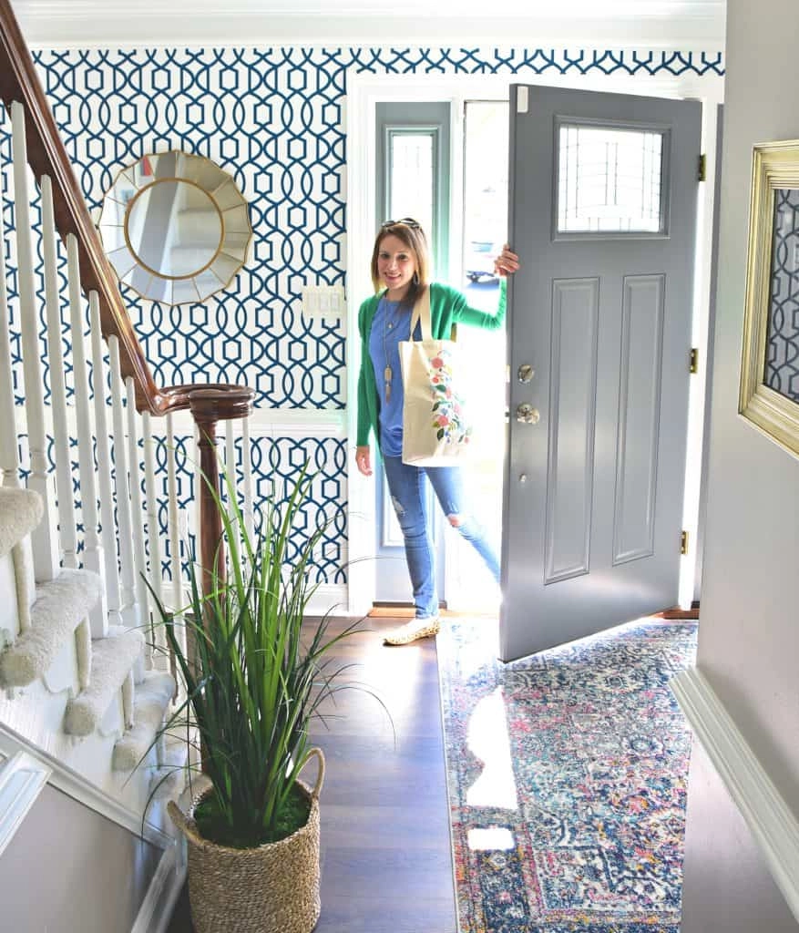 Kate poses in the updated entryway after the makeover; new geometric patterned wallpaper on the walls, a new area run, and a plant add a much needed update!