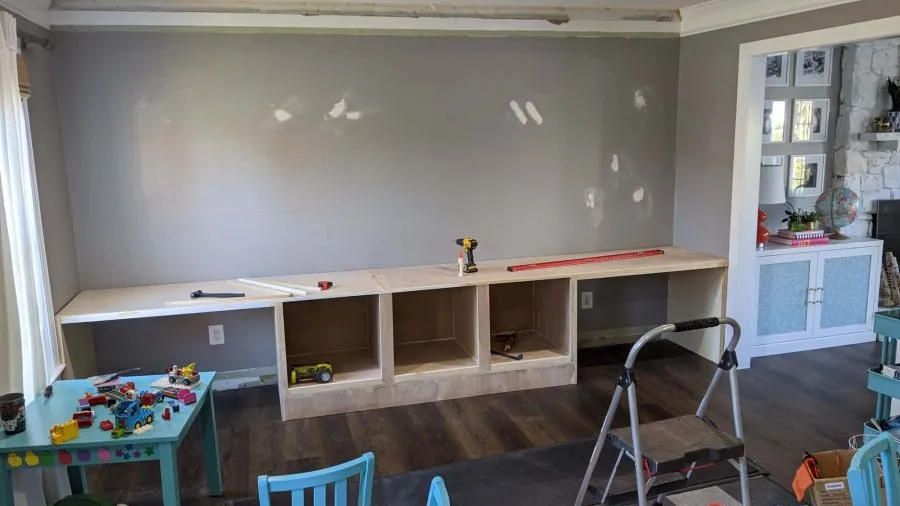 An in-progress photo of the DIY built-in kids desk and bookshelf in the new playroom; this image shows a bare wall with just the frame of the built in desk and storage area.